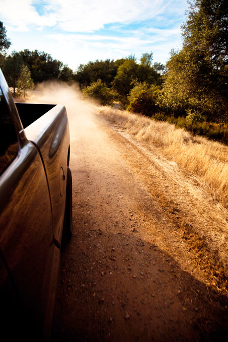 Truck-driving-down-dirt-road