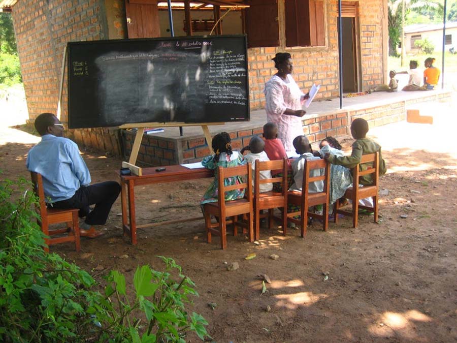 Mr. Clément Feizouré (left), Director of Ahdieh Foundation, visits a class at a community school in Bangui.