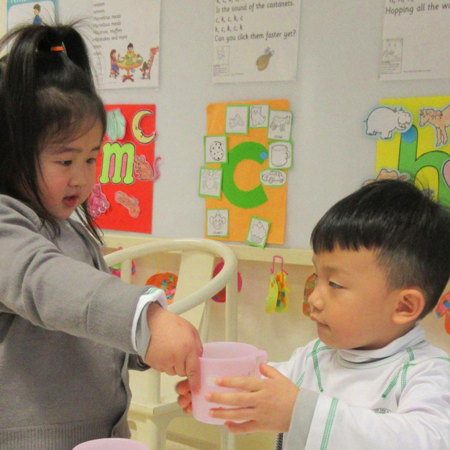 Service is integrated into the School of the Nations’ curriculum. Here, a kindergarten student offers water to her classmate as part of a lesson.