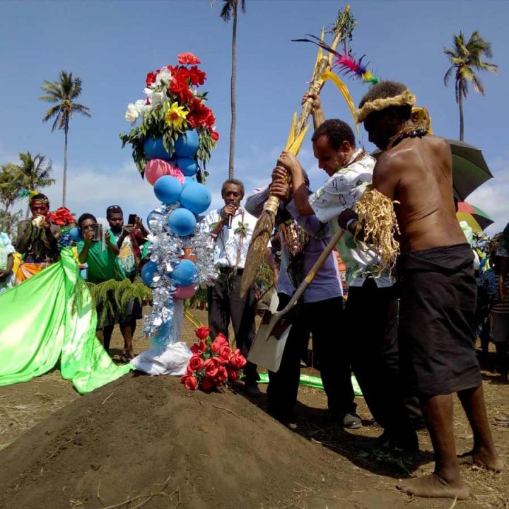 Foreign Minister Ralph Regenvanu and President of the Malvatumauri National Council of Chiefs Willie Plasua together drive the kakel—a traditional wooden spade—into the soil, symbolizing the start of construction on the local Baha’i House of Worship on the island of Tanna, Vanuatu.