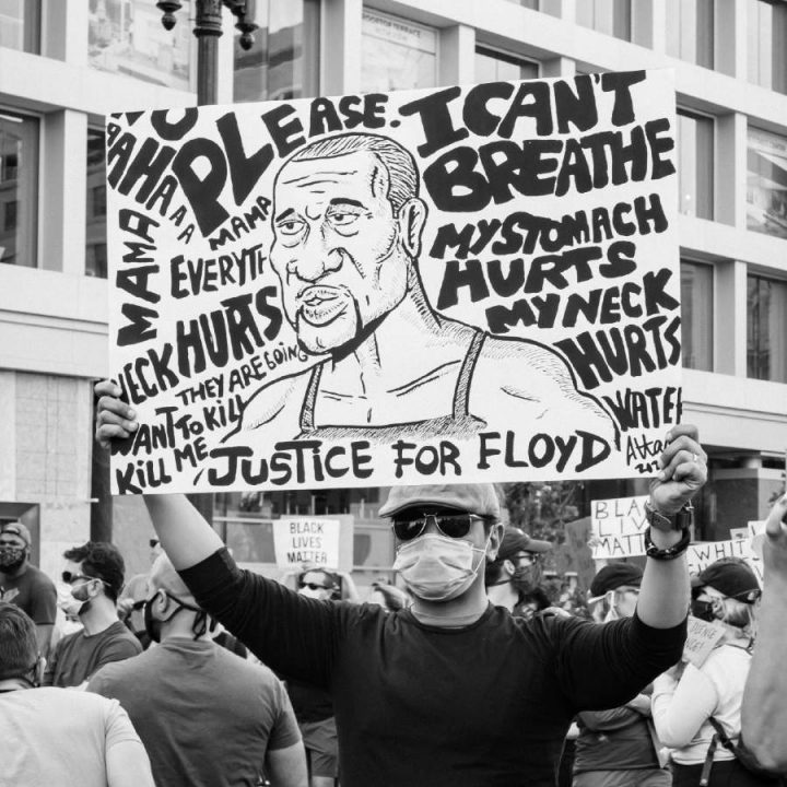 A man holding up a poster in honor of George Floyd.