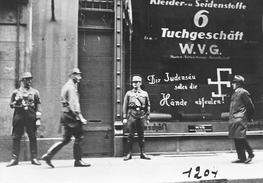 More than 50 years after Baha'u'llah's passing Nazi storm troopers are seen guarding a Jewish-owned business in Vienna shortly after the Anschluss. The graffito on the store window reads, “You Jewish pig, may your hands rot off!”