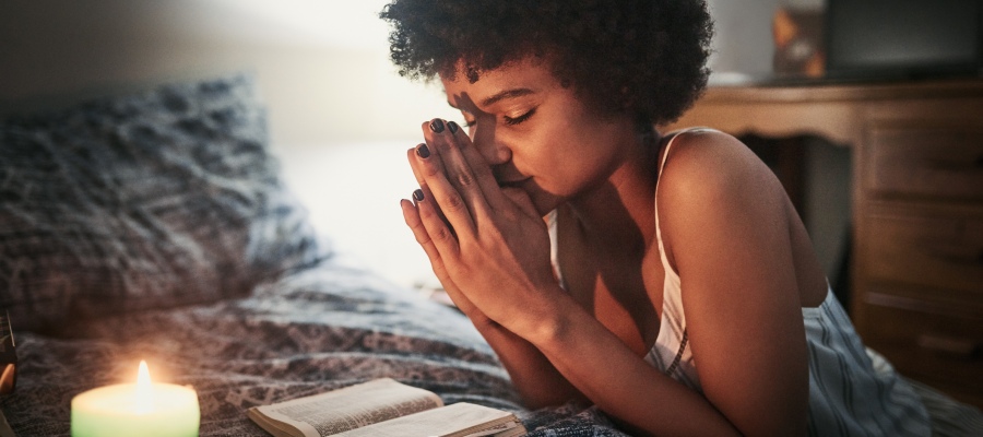 a woman praying near candlelight before bed