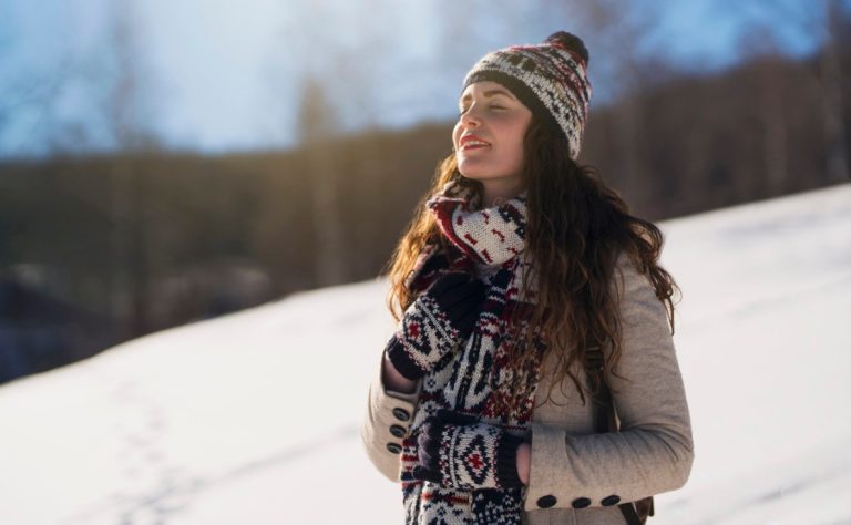 A woman standing on a snowy hill, gazing at the sky in quiet contemplation. A representation of spirituality and introspection.