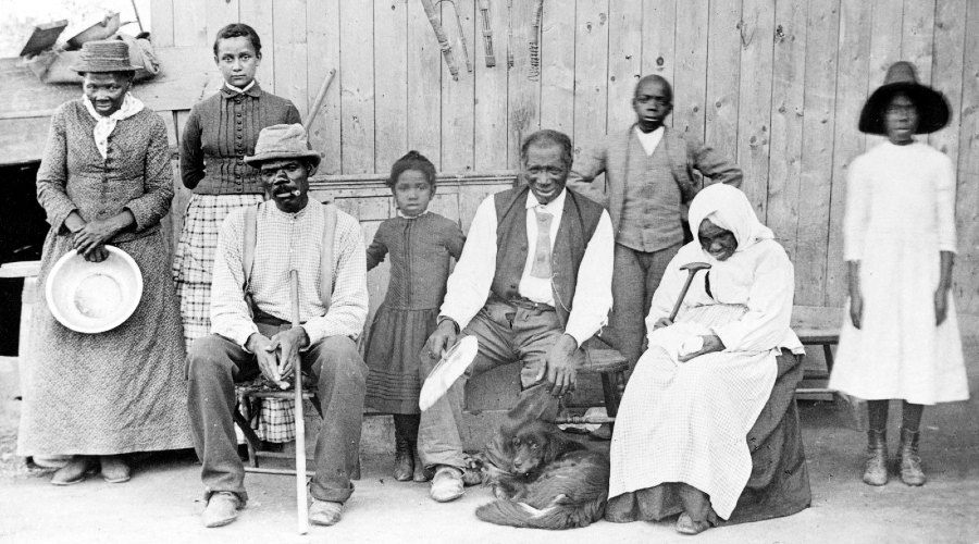 Harriet Tubman in 1887 (far left), with her husband Nelson Davis (seated, with cane), their adopted daughter Gertie (beside Harriet), and other family members, neighbors, and elderly boarders at her home in Auburn, New York