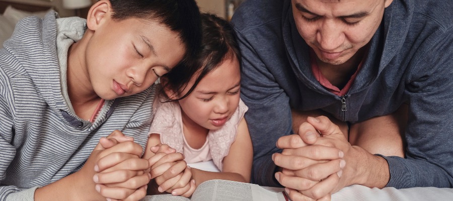 children praying with their father