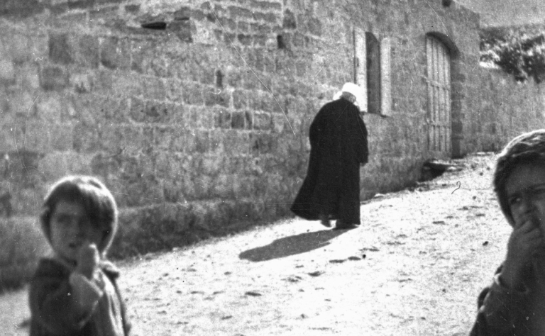 ‘Abdu’l-Bahá walking up Haparsim Street with three kids eating sweets that ‘Abdu’l-Bahá just gave them, c. 1920