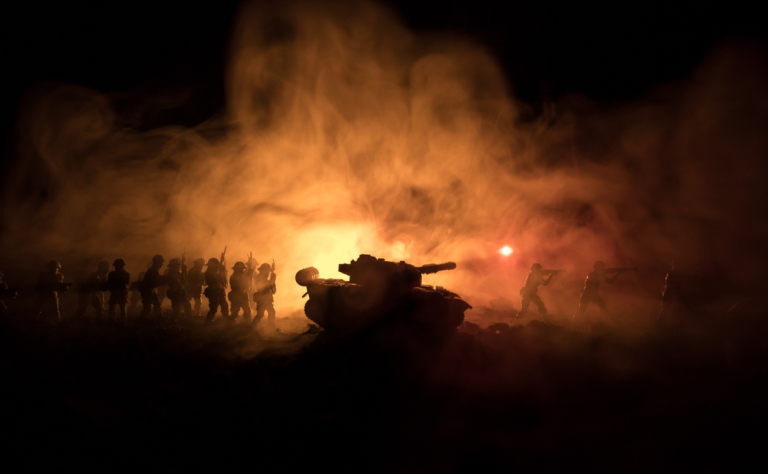 Silhouettes of world war soldiers below cloudy horizon at night.